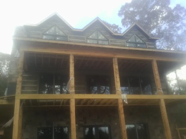 Dormers and porch framing on a large log home under construction — Roof Coating work by our crew in Laclede