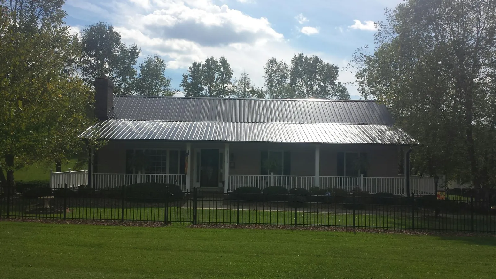 Gray metal roof on a brick ranch with a full width front porch — Gutter Guard Installation work by our crew in Laclede
