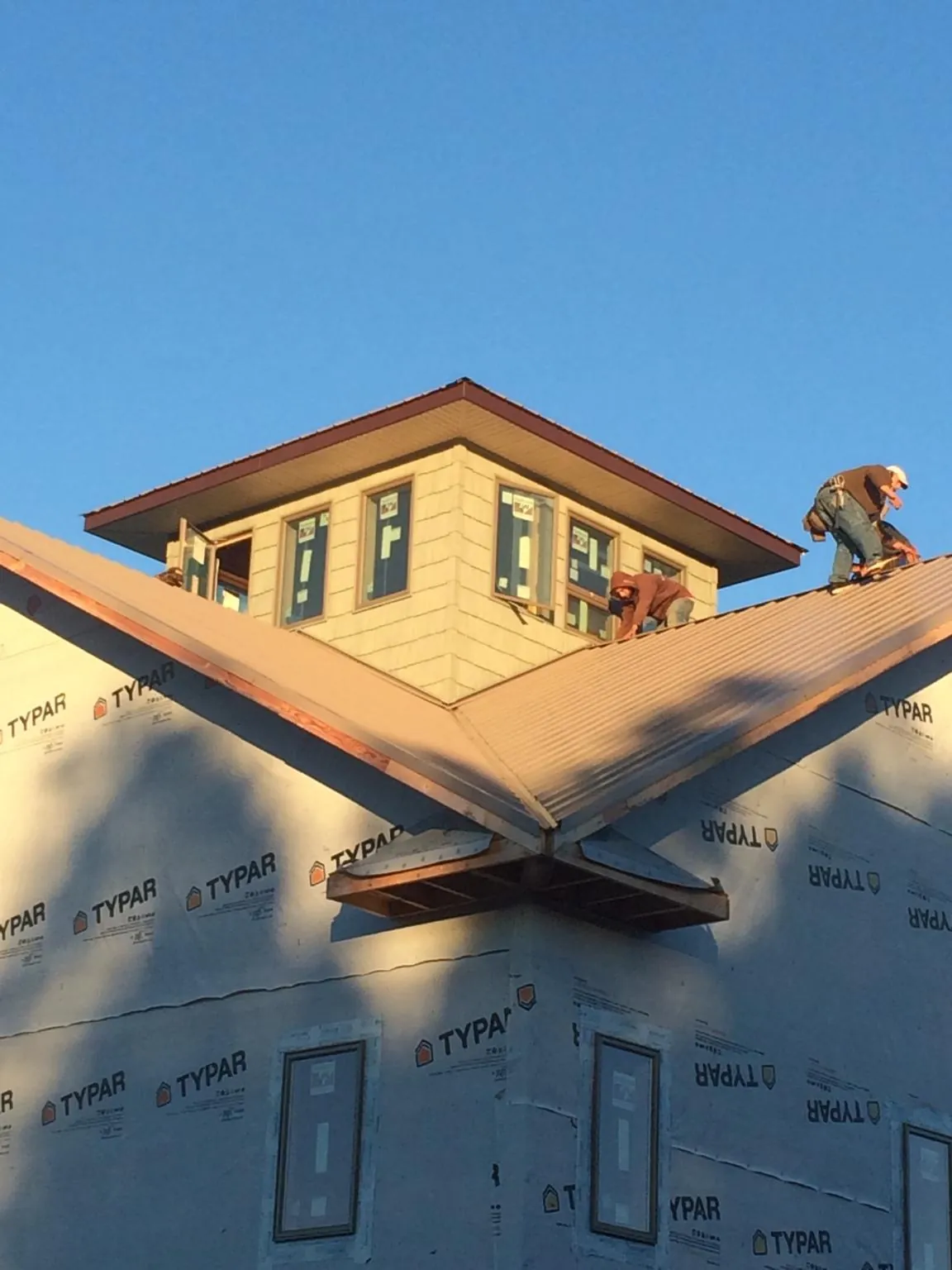Roofers working around a rooftop cupola on a new metal roof at sunset — Roof Waterproofing in Laclede by Roofing Brothers